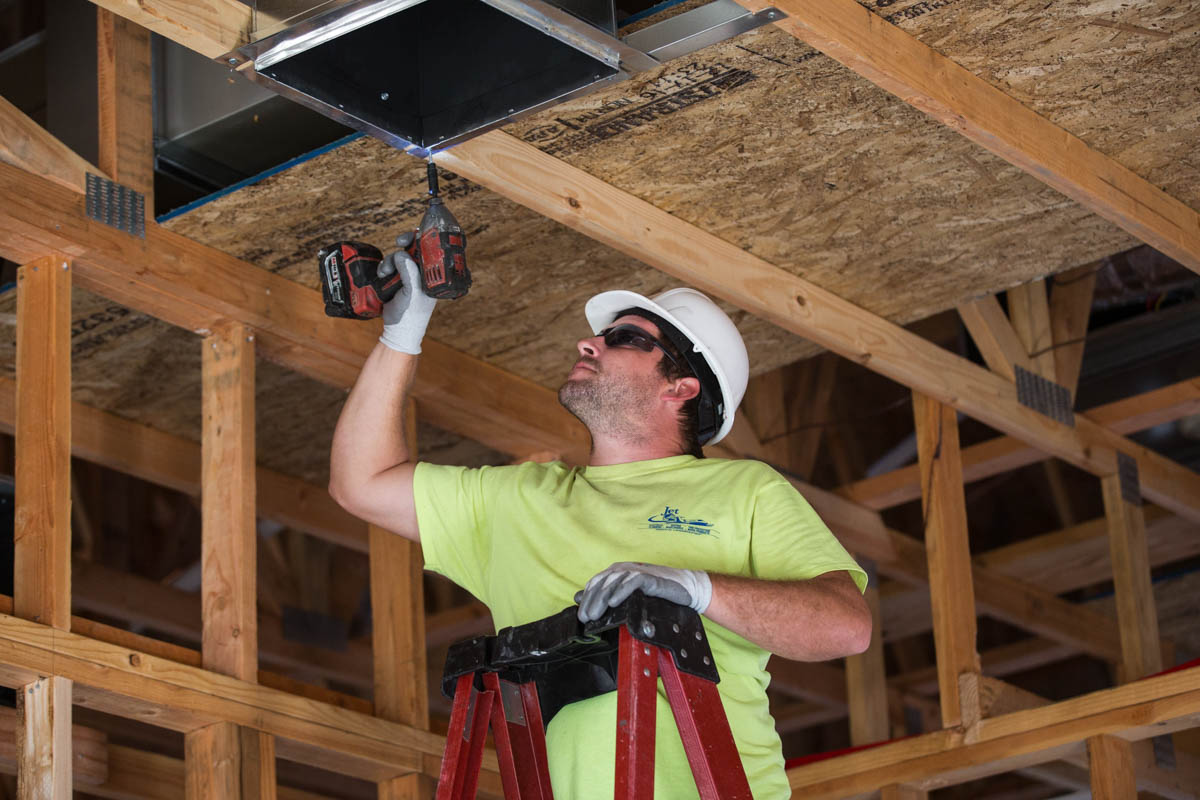 Man on ladder installing HVAC vent