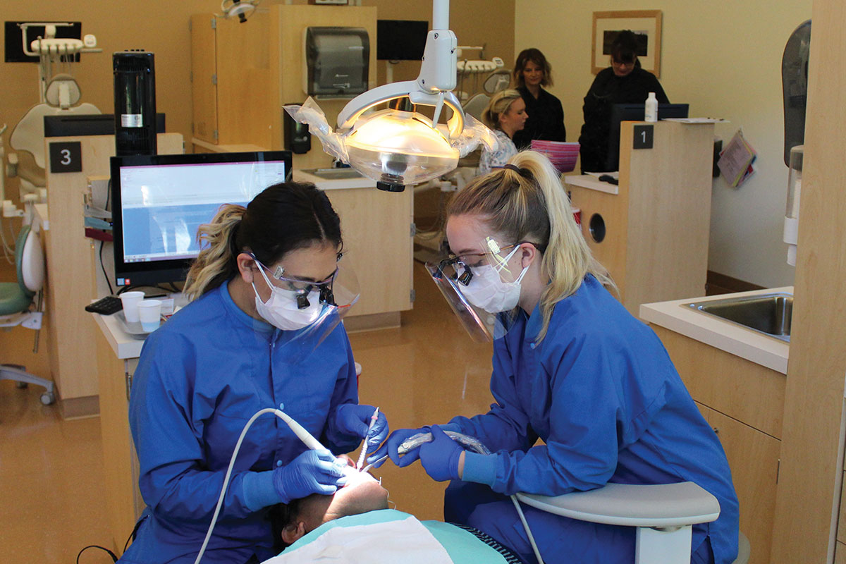 two female dental hygienists working on man 