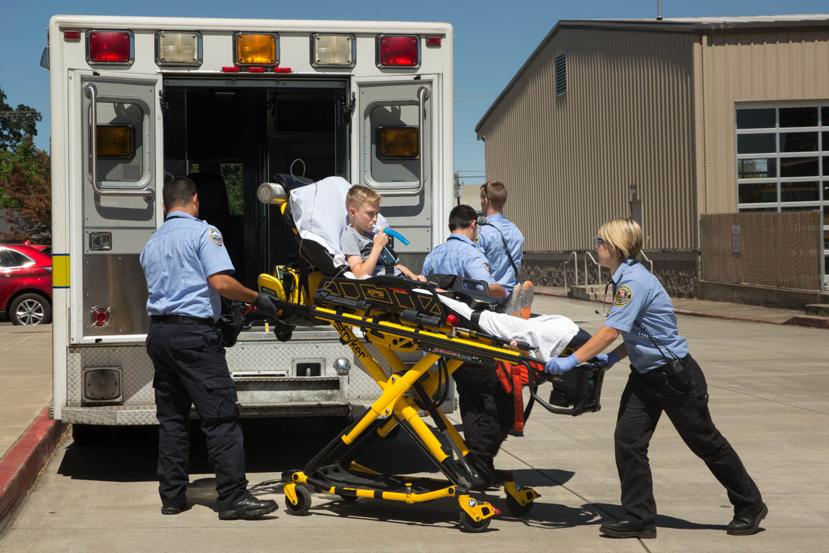 EMT's helping put gurney with a child on it into the ambulance