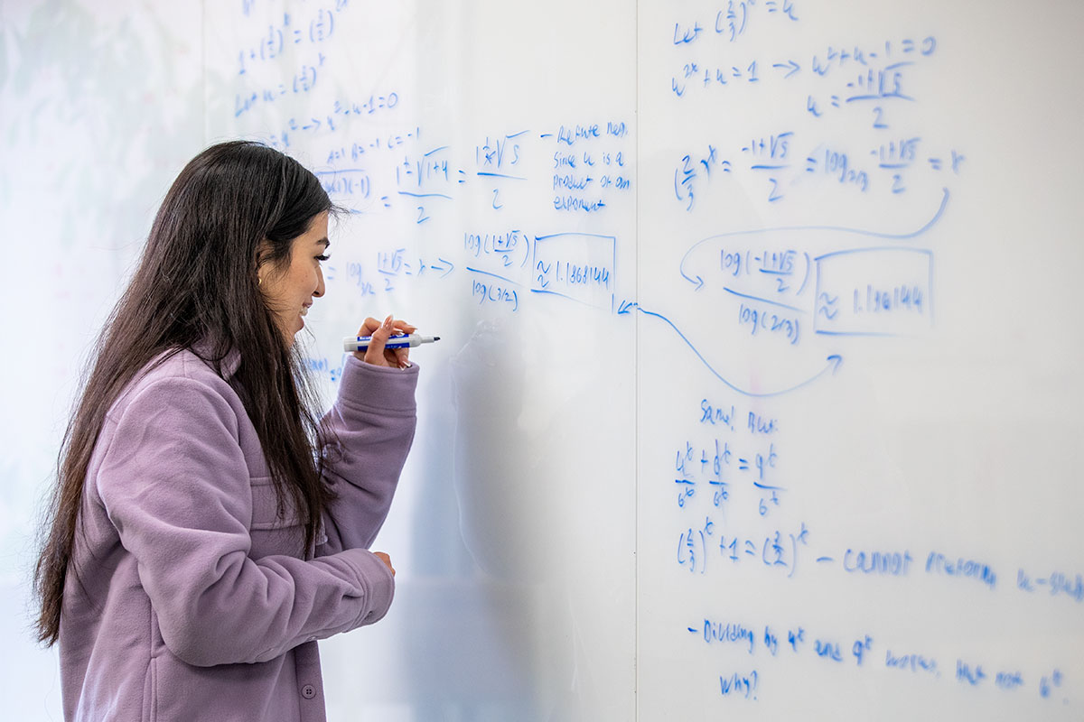 Woman doing calculations on a whiteboard